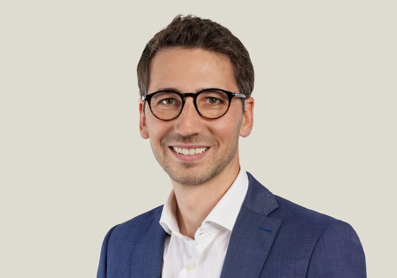 Mitarbeiterporträt von Mann mit Brille im blauem Anzug