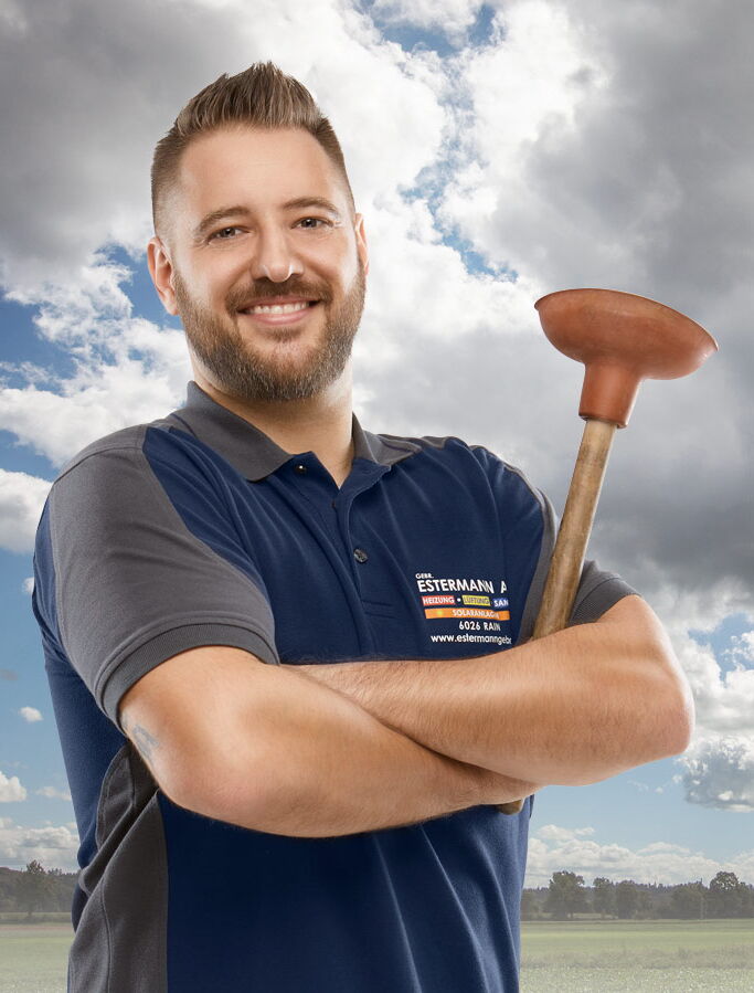 Mitarbeiterfotos Luzern - Mann mit blauem T-Shirt und Bart hält WC-Pümpel