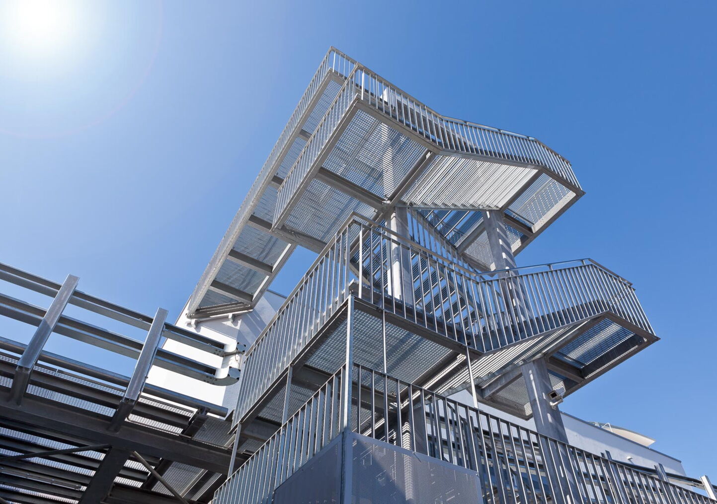 Industriefotografie: Stahltreppe mit Geländer vor blauem Himmel