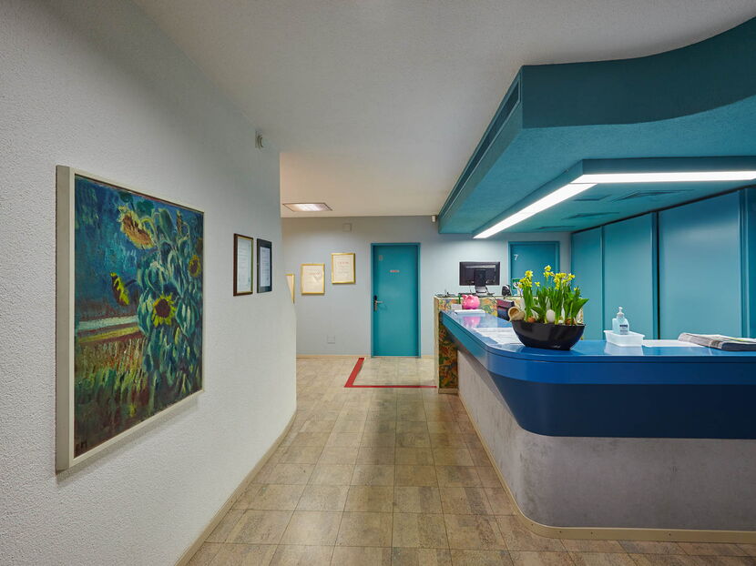 Blaue Empfangstheke in Arztpraxis mit Bildern und Diplome an der Wand