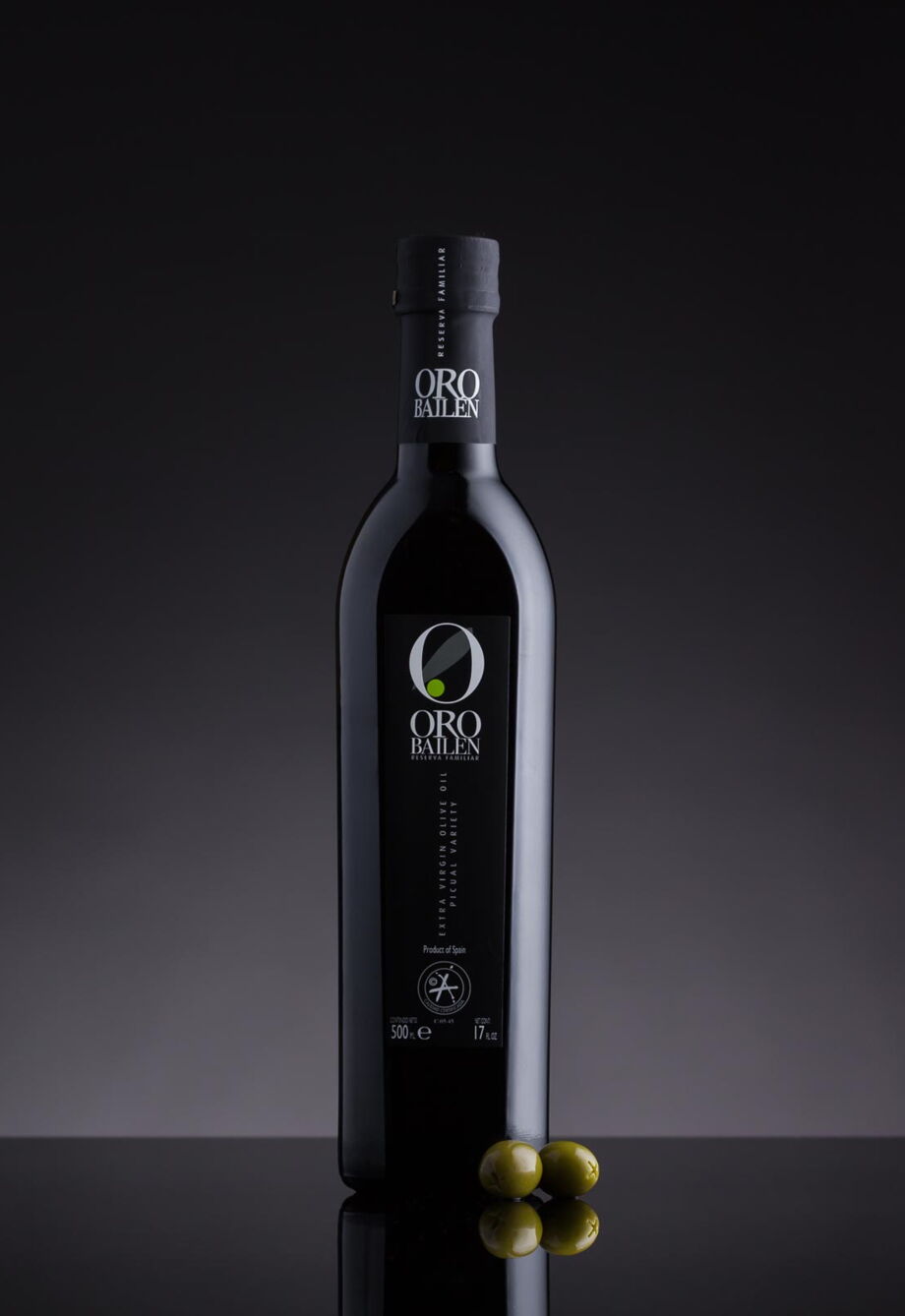 Werbefotografie Schwarze Olivenöl Flasche mit zwei grünen Oliven