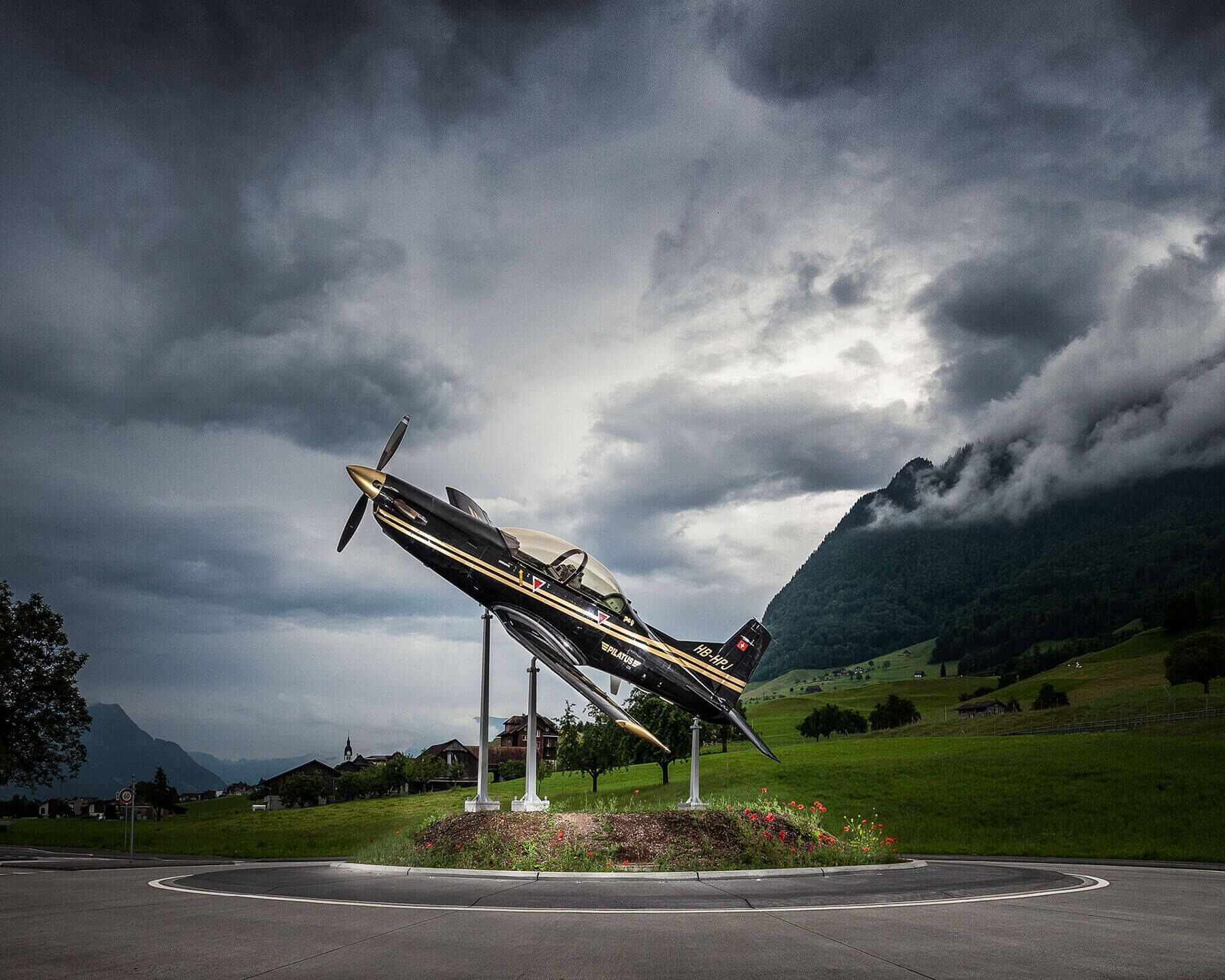 Industriefotografie von schwarzem Flugzeug auf einem Kreisverkehr vor Berglandschaft