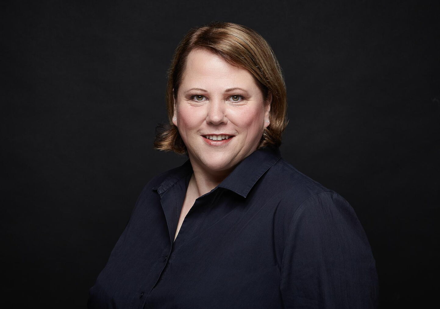 Businessfotografie: Frau in dunkelblauem Hemd vor schwarzem Hintergrund