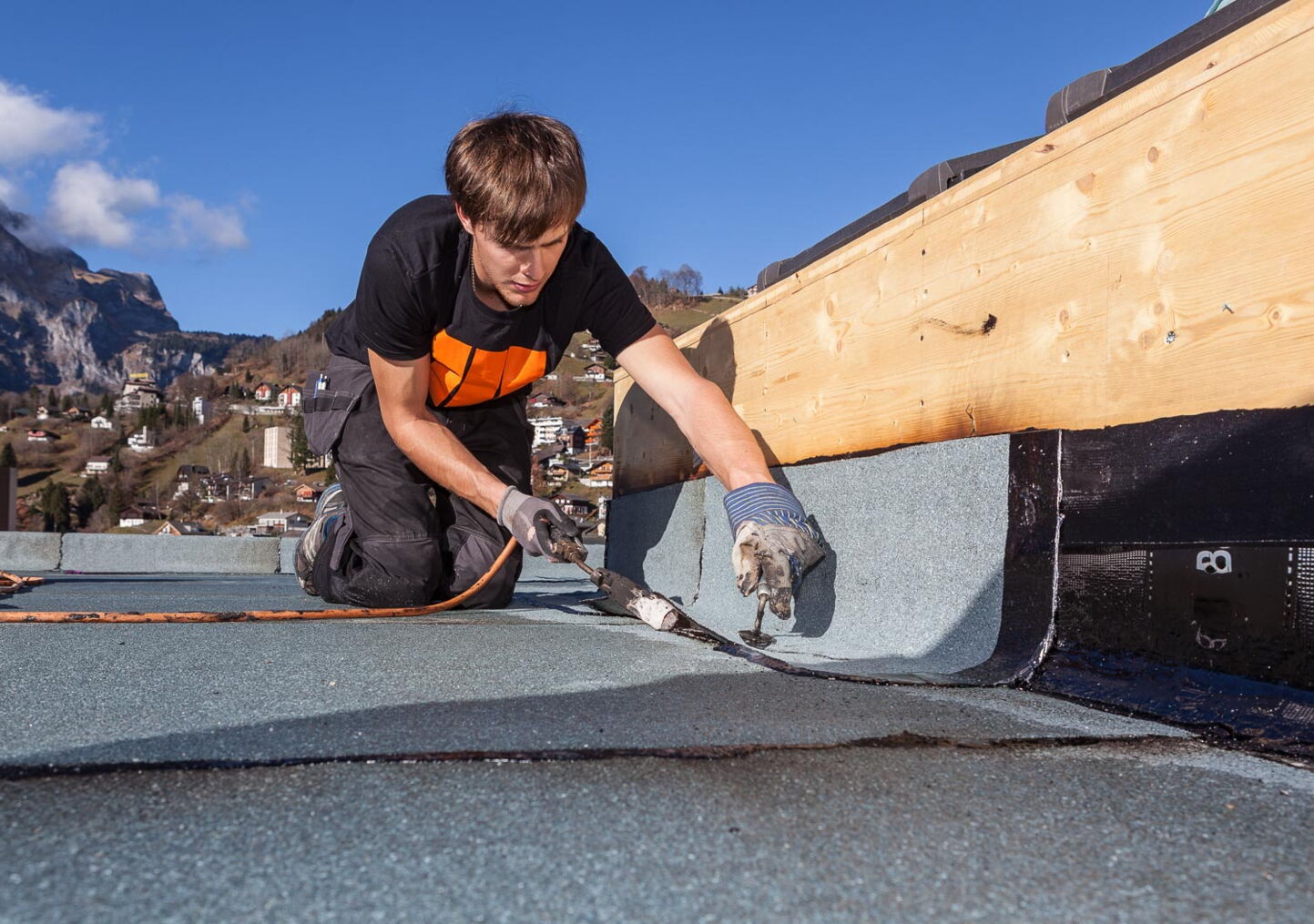 Industriefotografie eines Handwerkers mit Schweissbrenner bei Dachpappeverlegung