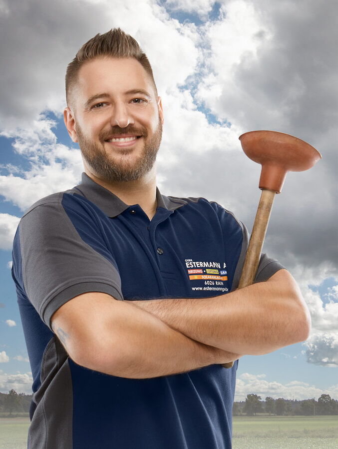 Mitarbeiterfotos Luzern - Mann mit blauem T-Shirt und Bart hält WC-Pümpel