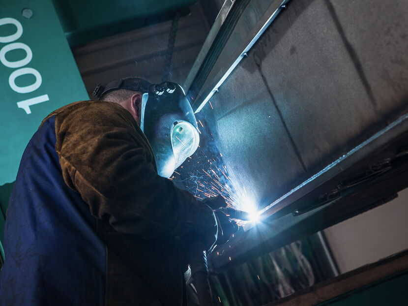 Industriefotografie: Schweisser mit Schild und Schweissanlage