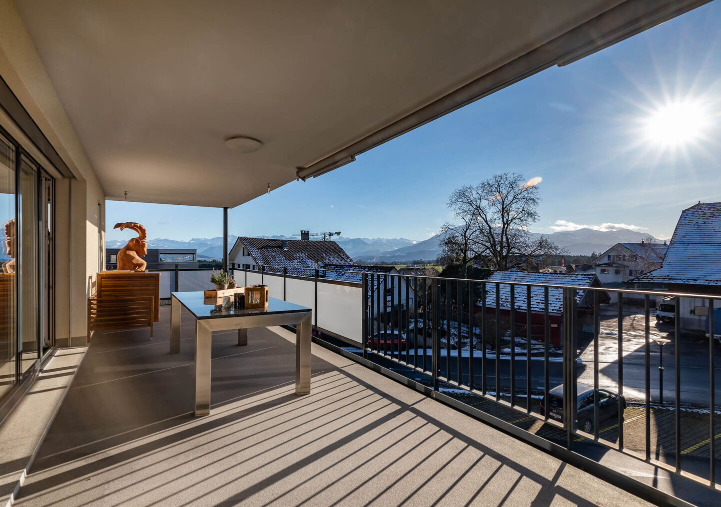 Immobilienfotografie: Grosser Balkon mit Staketengeländer und scheinender Sonne