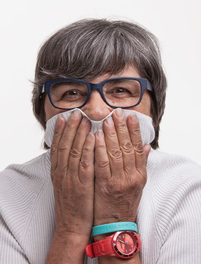 Grauhaarige Frau mit hochgezogenem Pulloverkragen über Gesicht