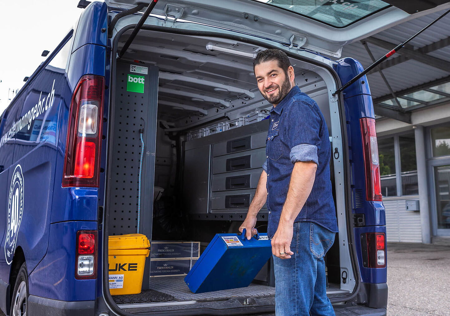 Industriefotograf Luzern - Sanitärmonteur vor blauem Fahrzeug mit blauem Metallkoffer