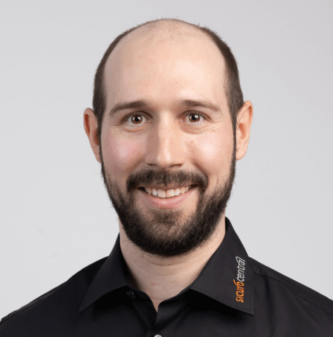 Männerportrait mit schwarzem Hemd, dunklem Bart und Stirnglatze